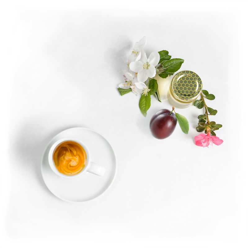 Med, slivka a kvety vedľa pohára kávy